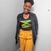 A smiling photo of Nikeisha Sewell Lewis wearing a Jamaican flag t-shirt