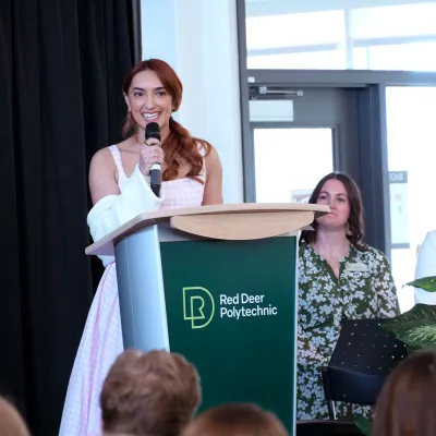Raya Weimer, a fourth-year nursing pinning candidate, stands behind a podium addressing her fellow studentsand their guests