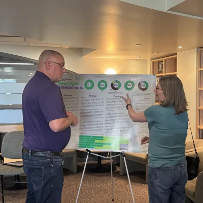 Two faculty discuss a poster showcasing research at the annual RoSA Awards
