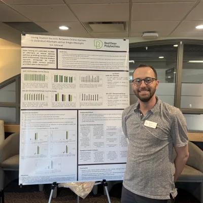 Tom Whitesell stands smiling in front of his poster explaining his research