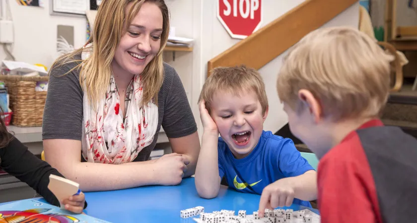 Child Care working playing a dice game with two children