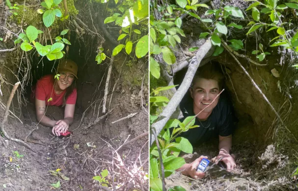 Researchers Meggy & Kyle smile while laying in the entrance of a bear's den.