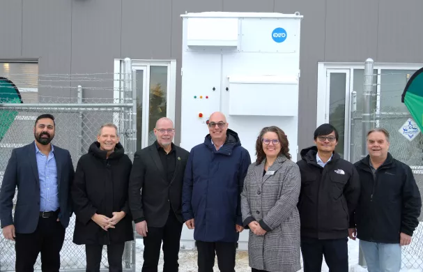 A group of representatives from RDP and Exro Technologies stands outside in front of the First Cell Driver Energy Storage System