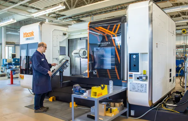 A technician operates a large Mazac printer in CIM-TAC research facility.