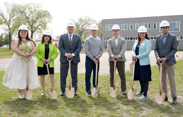 A group of RDP and Government of Alberta reps wear hardhats while holding shovels