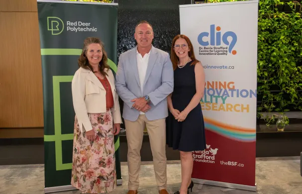 Dr. Tonya WOlfe, Tony Weeks, and Catherine Laing stand smiling in front of RDP and CLIQ banners