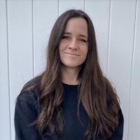 Jolene, with long brown hair, smiles slightly at the camera.