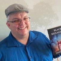 Headshot of Dan Whiteside holding his book "Black Menagerie"