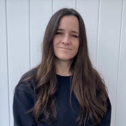 Jolene, with long brown hair, smiles slightly at the camera.