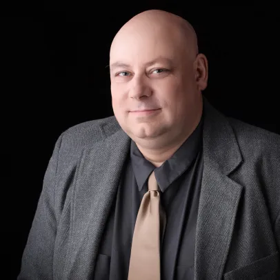 James Wilson sits against a dark background and looks into the camera