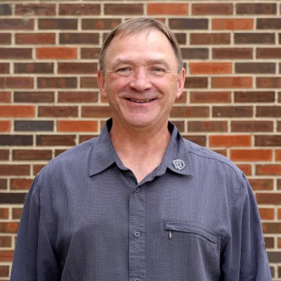 A smiling headshot of Bill Petrosenko in front of a brick wall