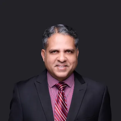 Smiling headshot of Raf Mohammed in a dark suit and a burgundy shirt and tie