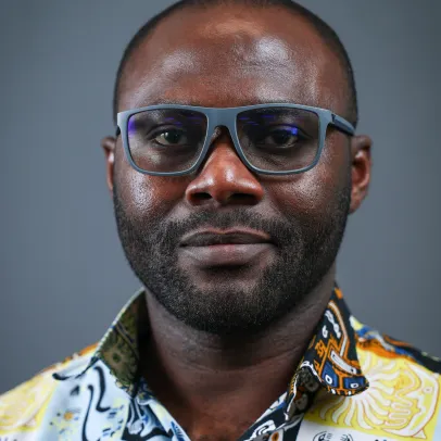 Isaac wears dark grey glasses and a vibrant shirt with various prints