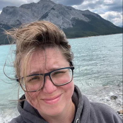 A selfie. Dawn squints into the camera, the wind blowing her hair as she stands in front of a lake in the mountains