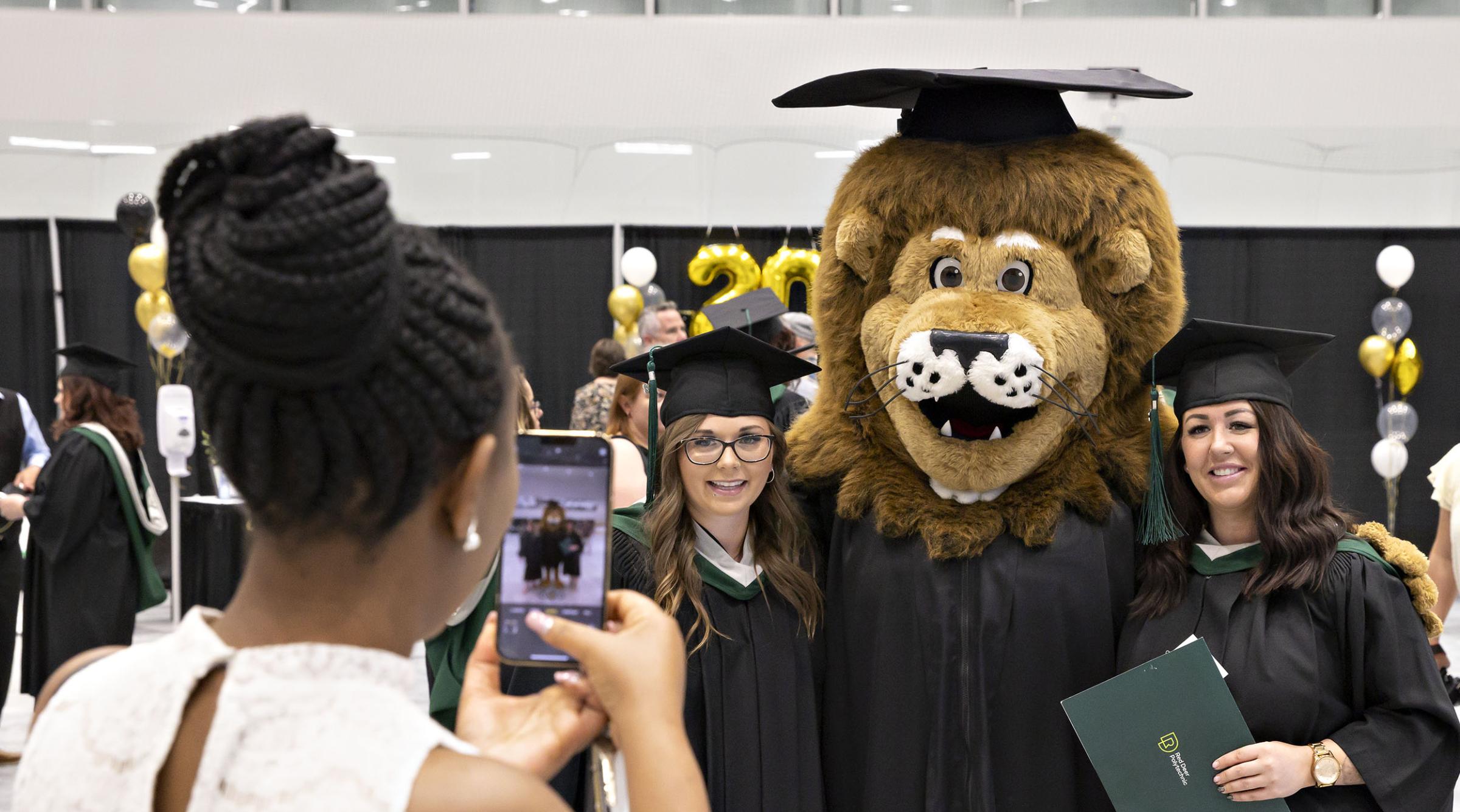 Graduates pose for photo with RDP's mascot, Rufus, before ceremony