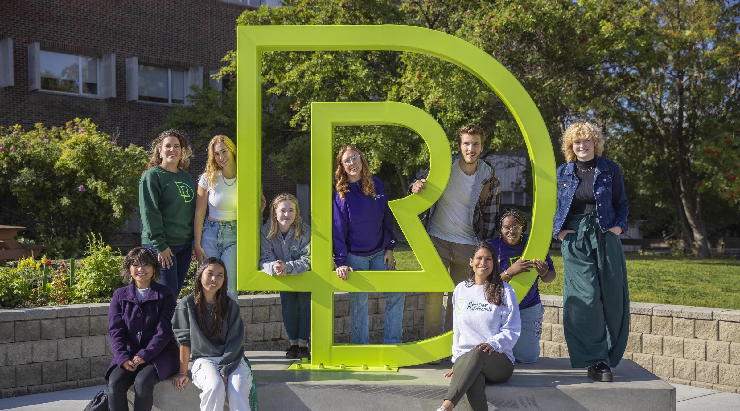 Students sitting by RDP sculpture outside main campus entrance