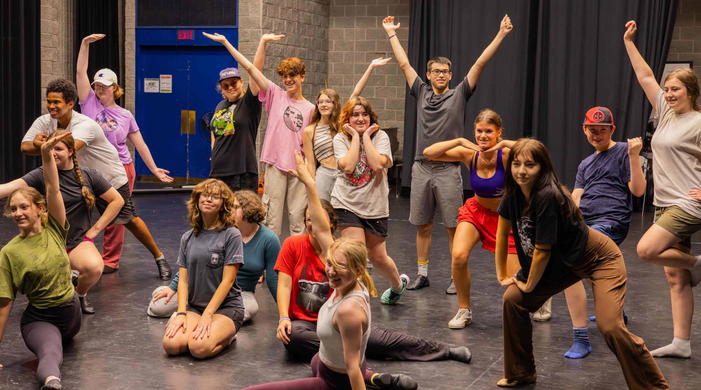 A group of teenagers posing in various dance positions on a stage