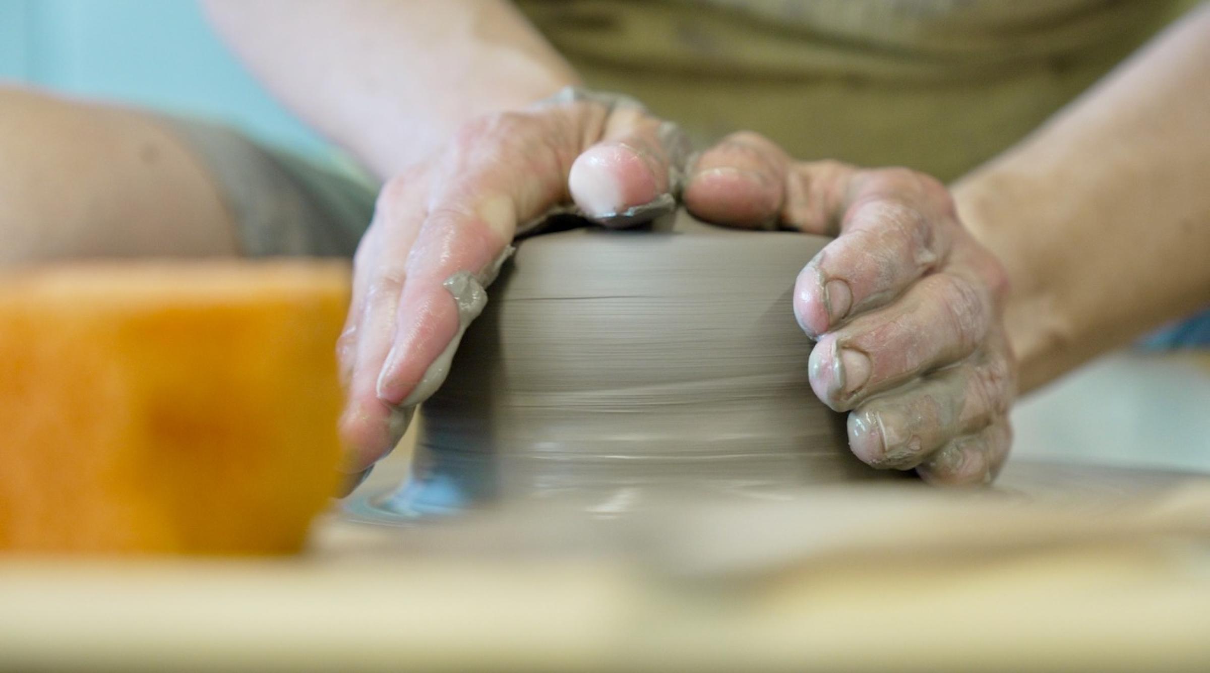 Close up of hands forming clay on a potter's wheel