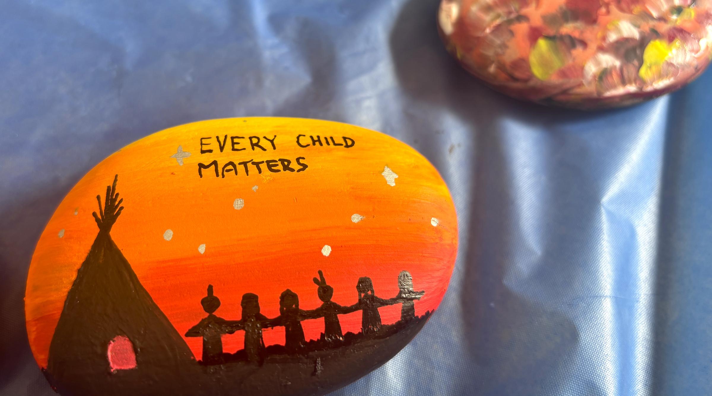 Rocks painted in bright orange with "Every Child Matters" in dark letters.