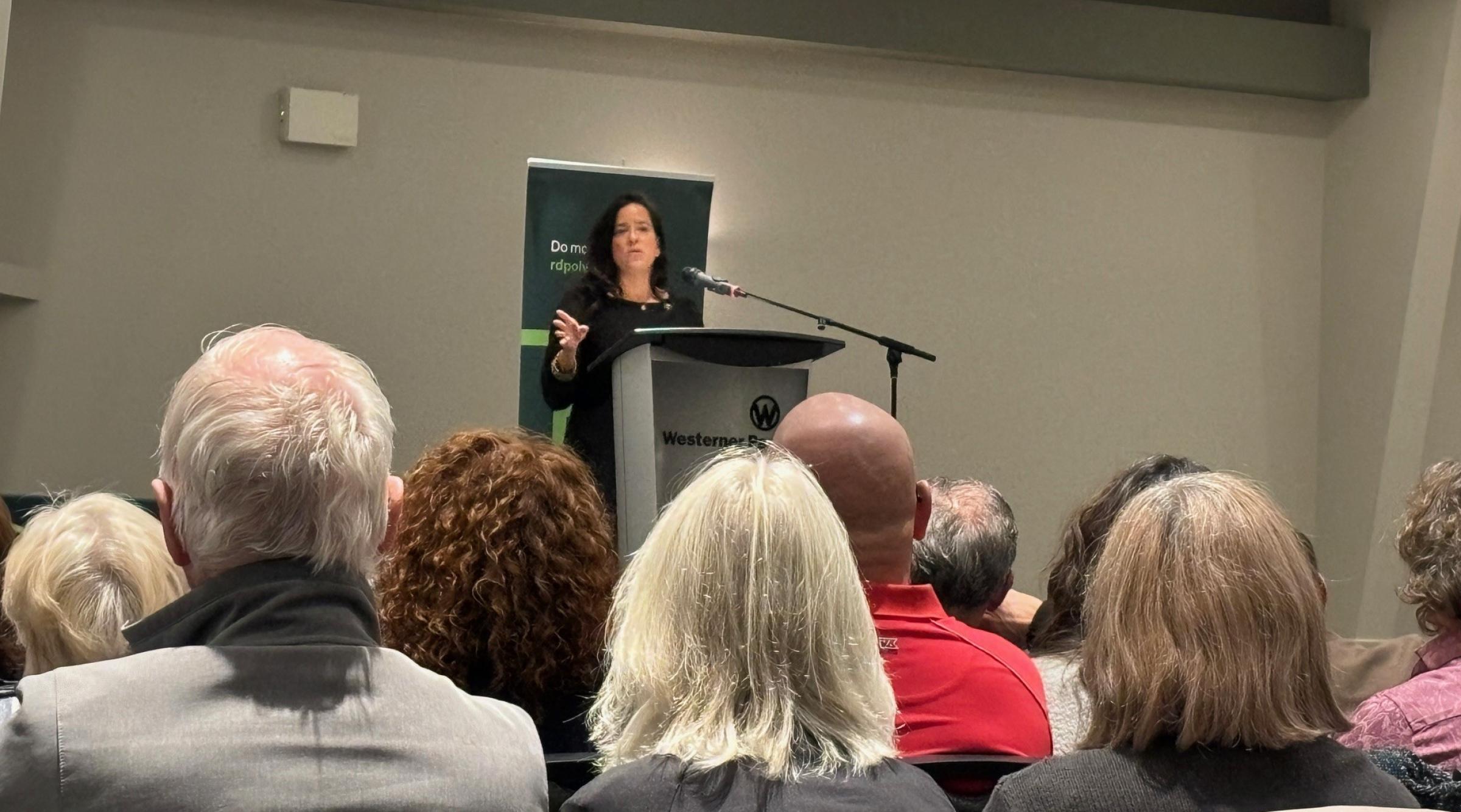 Jody Wilson-Raybould stands on a stage speaking to a seated crowd
