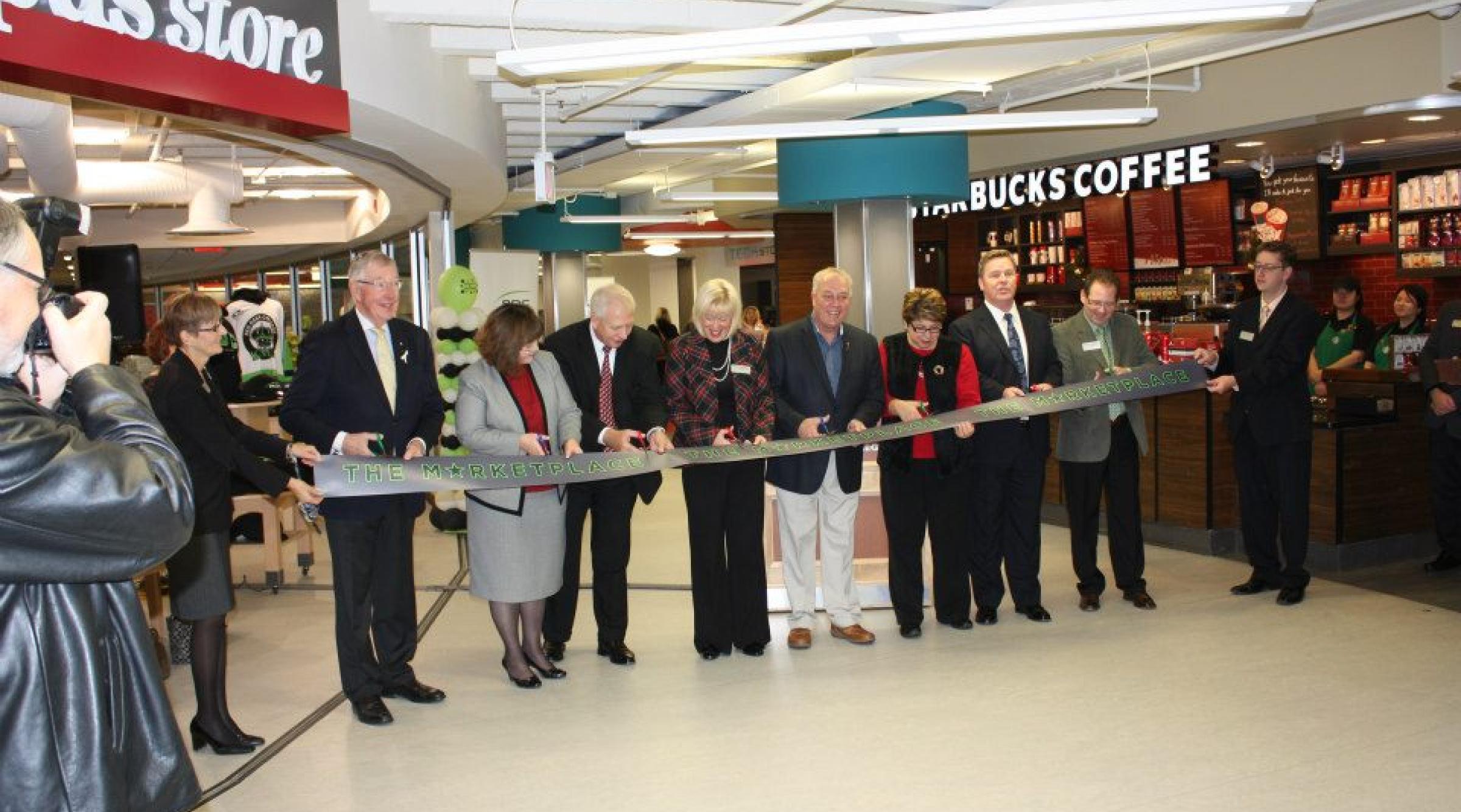 An archival photo of a group of people in suits cutting the ribbon in front of the Marketplace at RDC