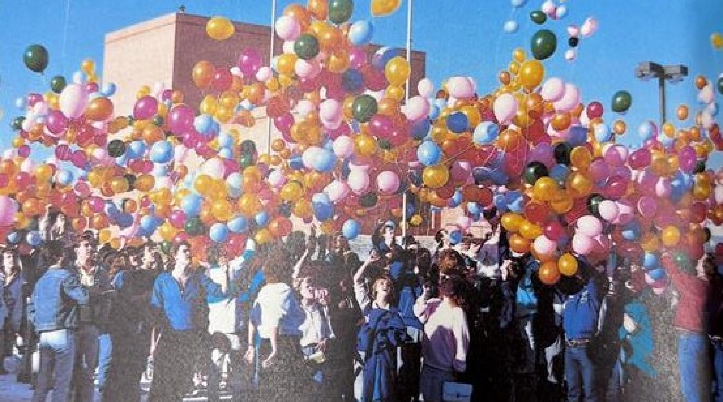 An older picture of a group of students releasing colourful ballons into the air in celebratino of the new Arts Building