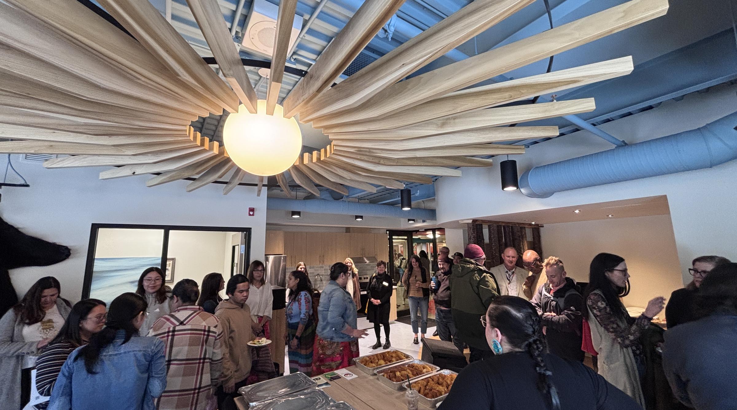 A large group explores the new Indigenous Student Centre. The space features dynamic architectural and lighting accents
