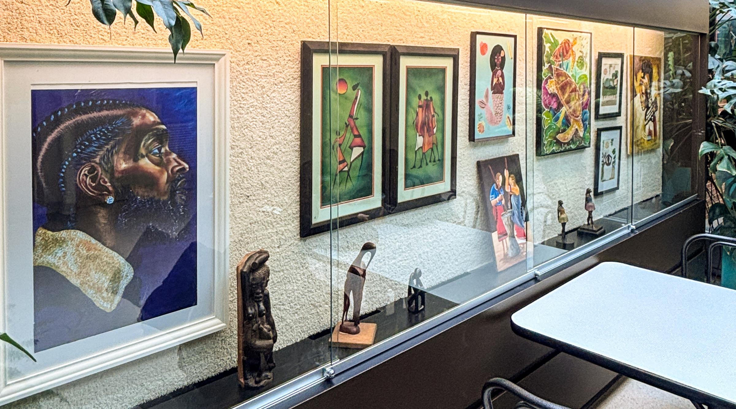 A display case featuring various paintings and small sculptures by Black Canadian artists.