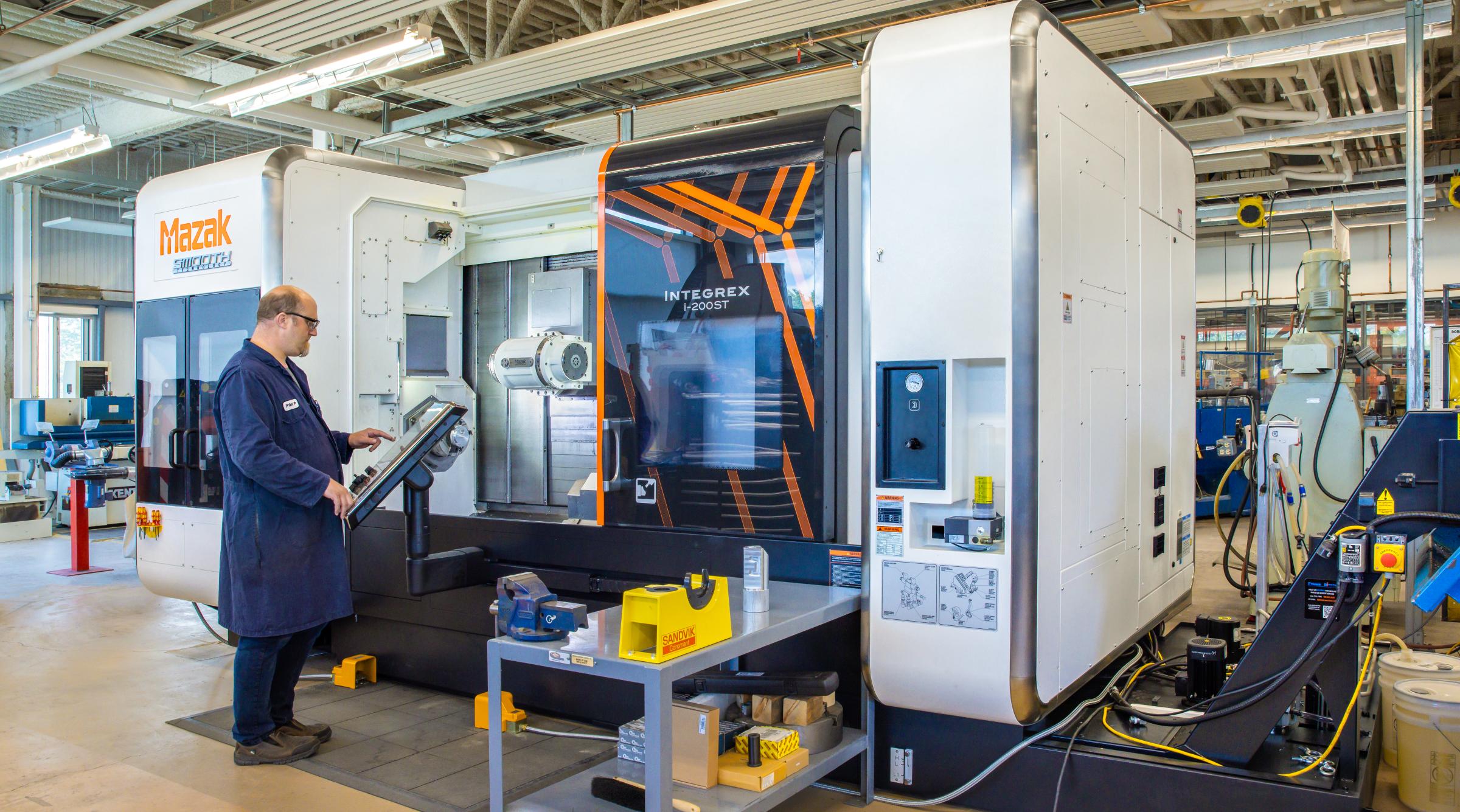 A technician operates a large Mazac printer in CIM-TAC research facility.
