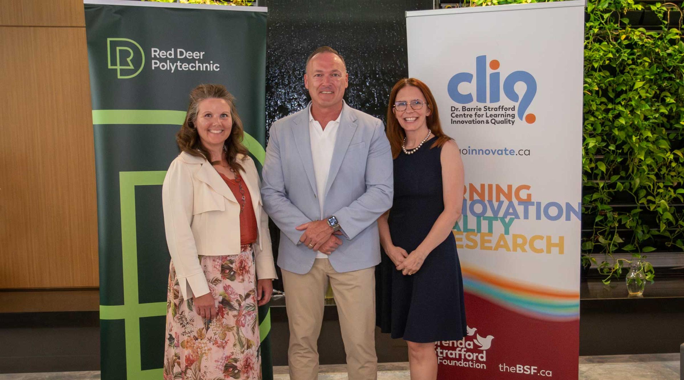Dr. Tonya WOlfe, Tony Weeks, and Catherine Laing stand smiling in front of RDP and CLIQ banners