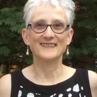 Valdis has short grey hair and black glasses.