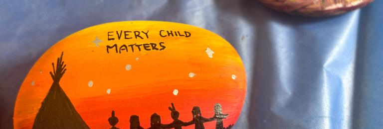 Rocks painted in bright orange with "Every Child Matters" in dark letters.