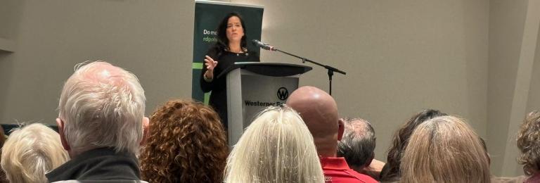 Jody Wilson-Raybould stands on a stage speaking to a seated crowd