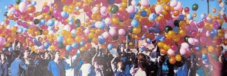 An older picture of a group of students releasing colourful ballons into the air in celebratino of the new Arts Building