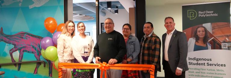 A group of RDP staff and students stand in front of an orange ribbon ready to cut it
