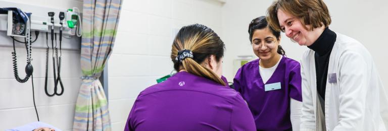 A group of student nurses and a faculty member practice their techniques on another student