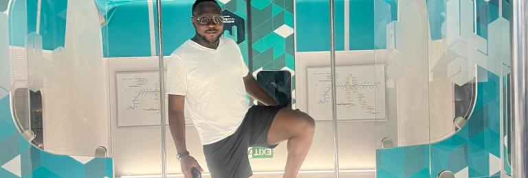 Emile Johnson stands in some futuristic exhibit reminiscing of a subway train, but upside down