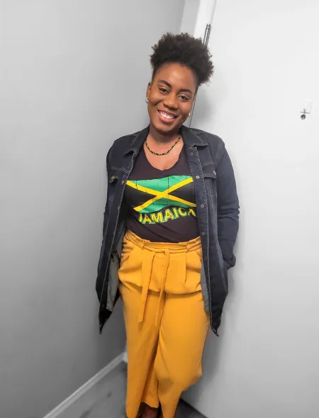 A smiling photo of Nikeisha Sewell Lewis wearing a Jamaican flag t-shirt