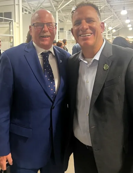 Ken Heather stands in a blue suit beside Stuart Cullum who wears a grey suit
