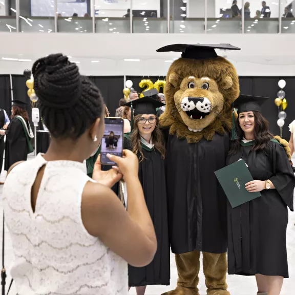 Graduates pose for photo with RDP's mascot, Rufus, before ceremony