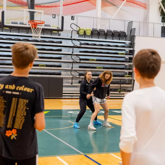 Student-athletes demonstrating basketball move to youth