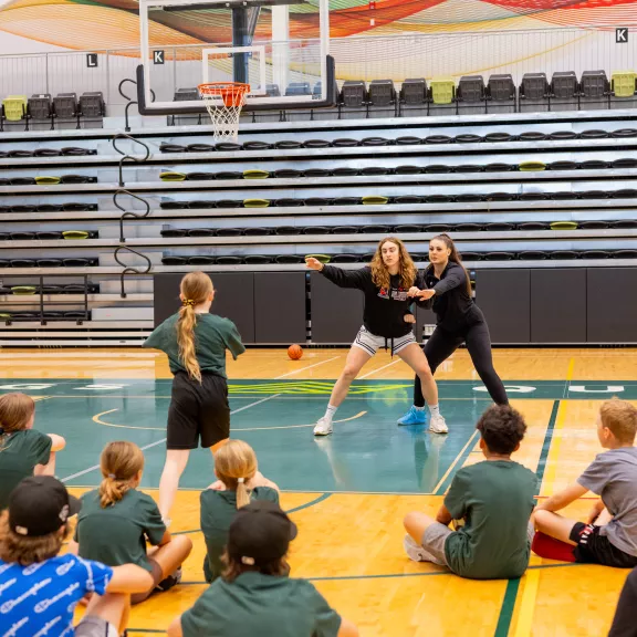 Students teaching a class of basketball youth in gym
