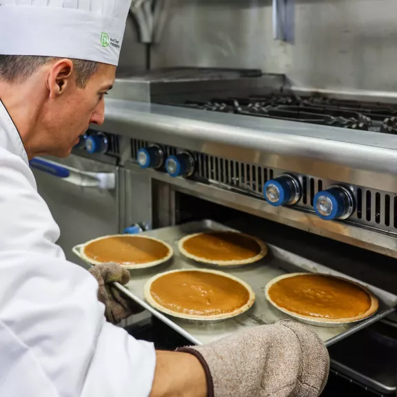 Cook instructor taking pumpkin pies out of oven