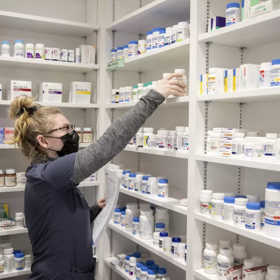Pharmacy Technician student reaching for medications