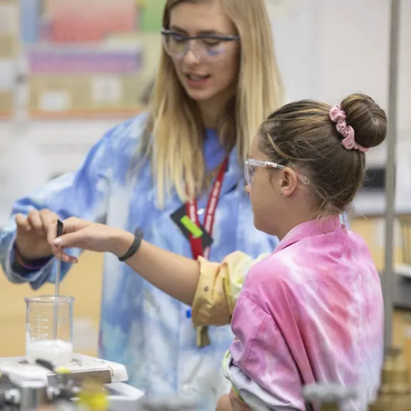 Student helping child in science lab