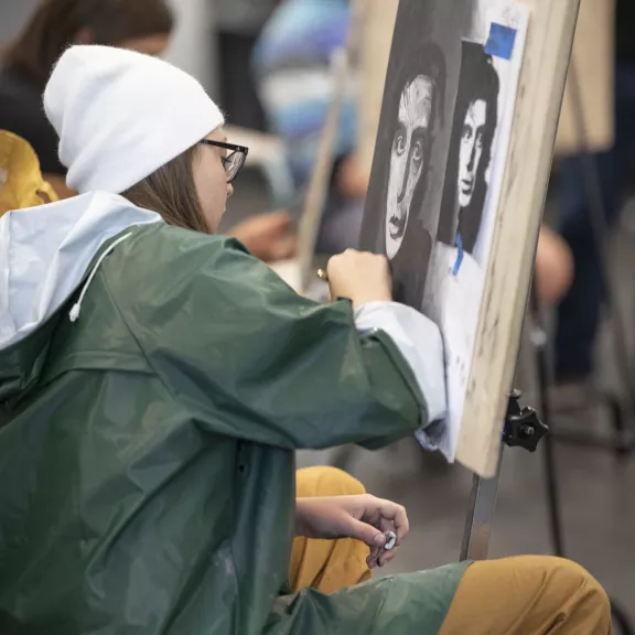 Young artist drawing on canvas with charcoal.