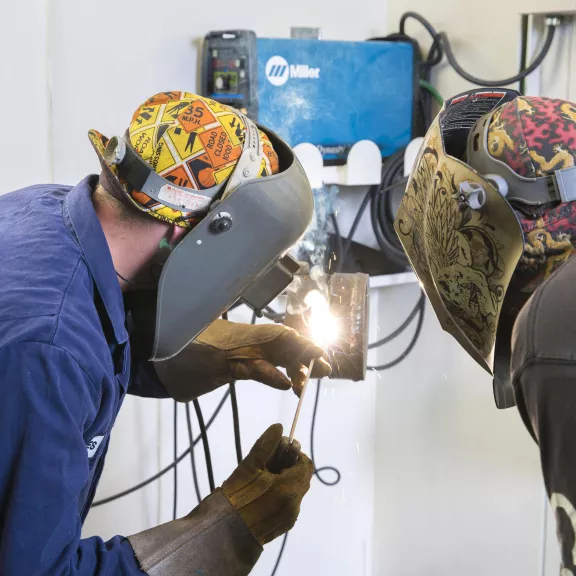 Welding instructor demonstrating to student