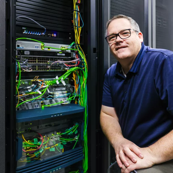 A technician standing beside a large computer terminal.