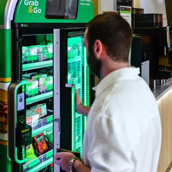 A student purchases ready-made subs at a green kiosk.