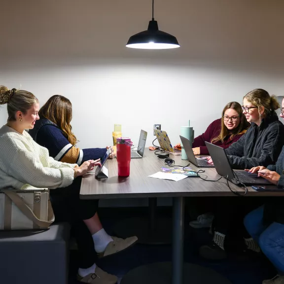 Students at a table in the Farside with laptops and drinks.